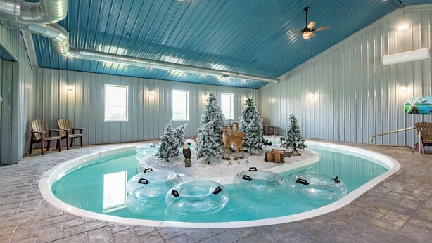 Una piscina interior con flotadores inflables, un árbol de Navidad y una estatua de ciervo.