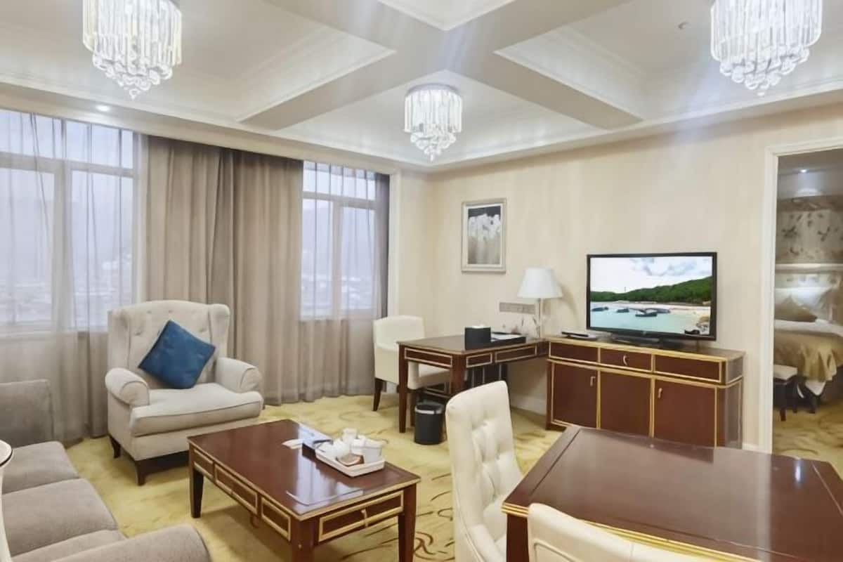 Ein Hotelzimmer mit großem Fenster, Fernseher, Schreibtisch, Stuhl und einer Couch.