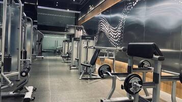 Un gimnasio con diversos equipos de ejercicio, incluyendo máquinas de pesas y pesas libres, dispuesto en un espacio amplio.