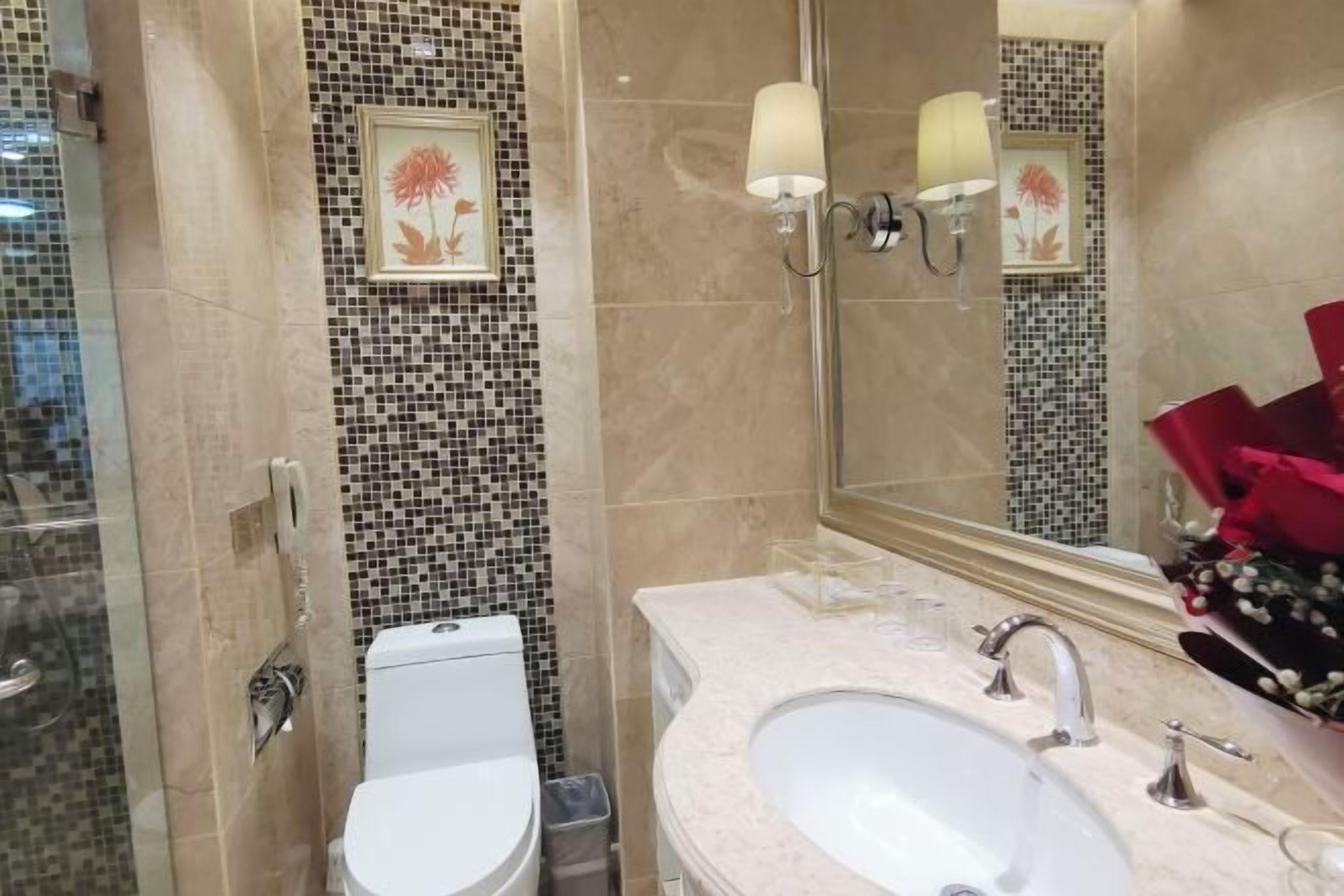 A bathroom with a toilet, bidet, sink, and a mirror with a floral design.