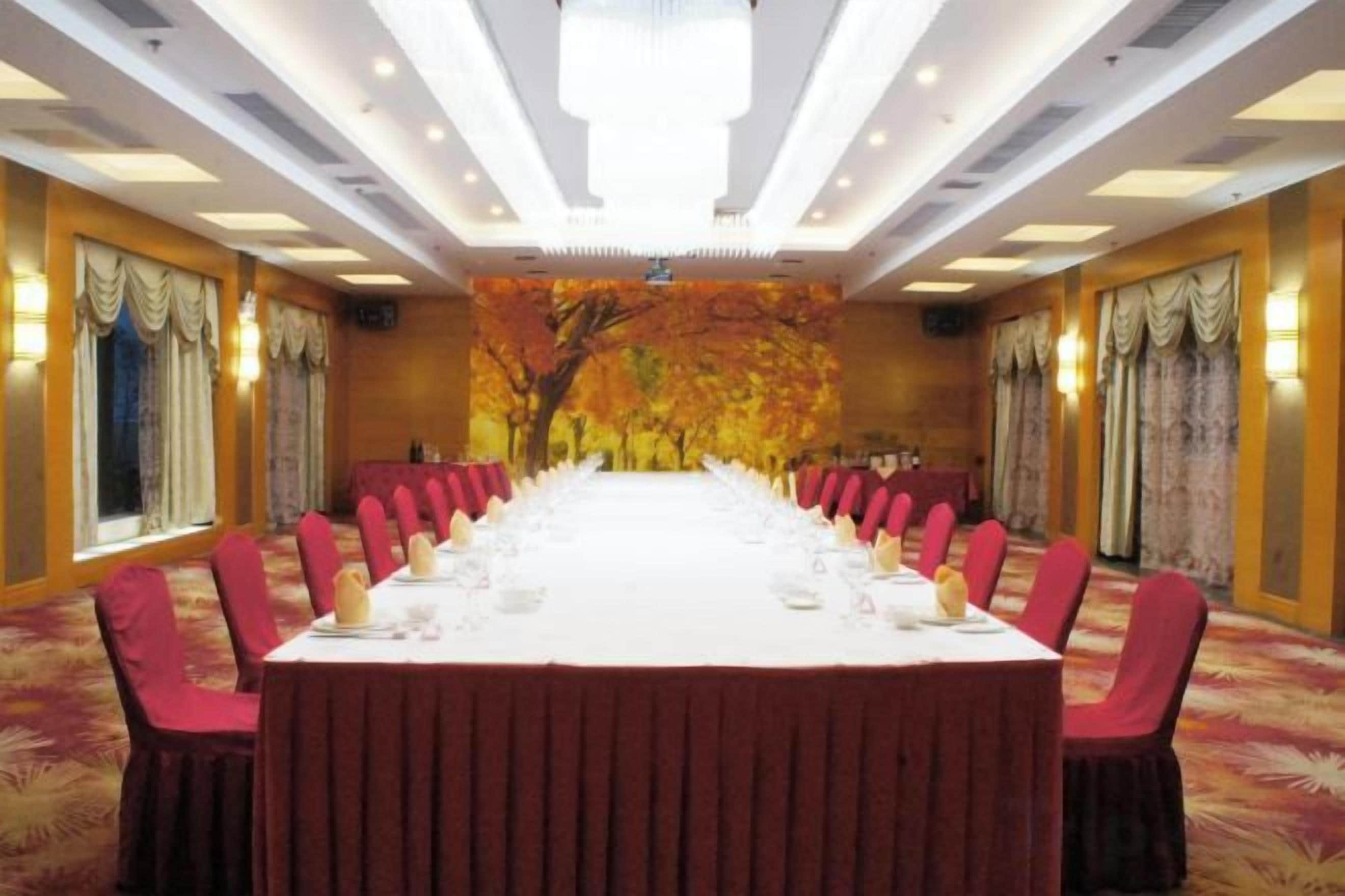 Una sala conferenze con un lungo tavolo apparecchiato per una riunione, circondato da sedie e con un murale decorativo sullo sfondo.