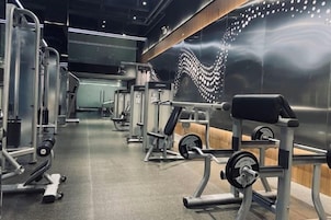 Un gimnasio con diversos equipos de ejercicio, incluyendo máquinas de pesas y pesas libres.