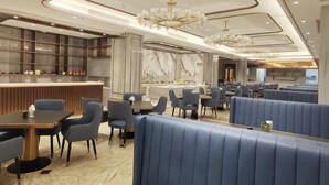 Un interior de restaurante moderno con mesas, una barra y una lámpara de araña.
