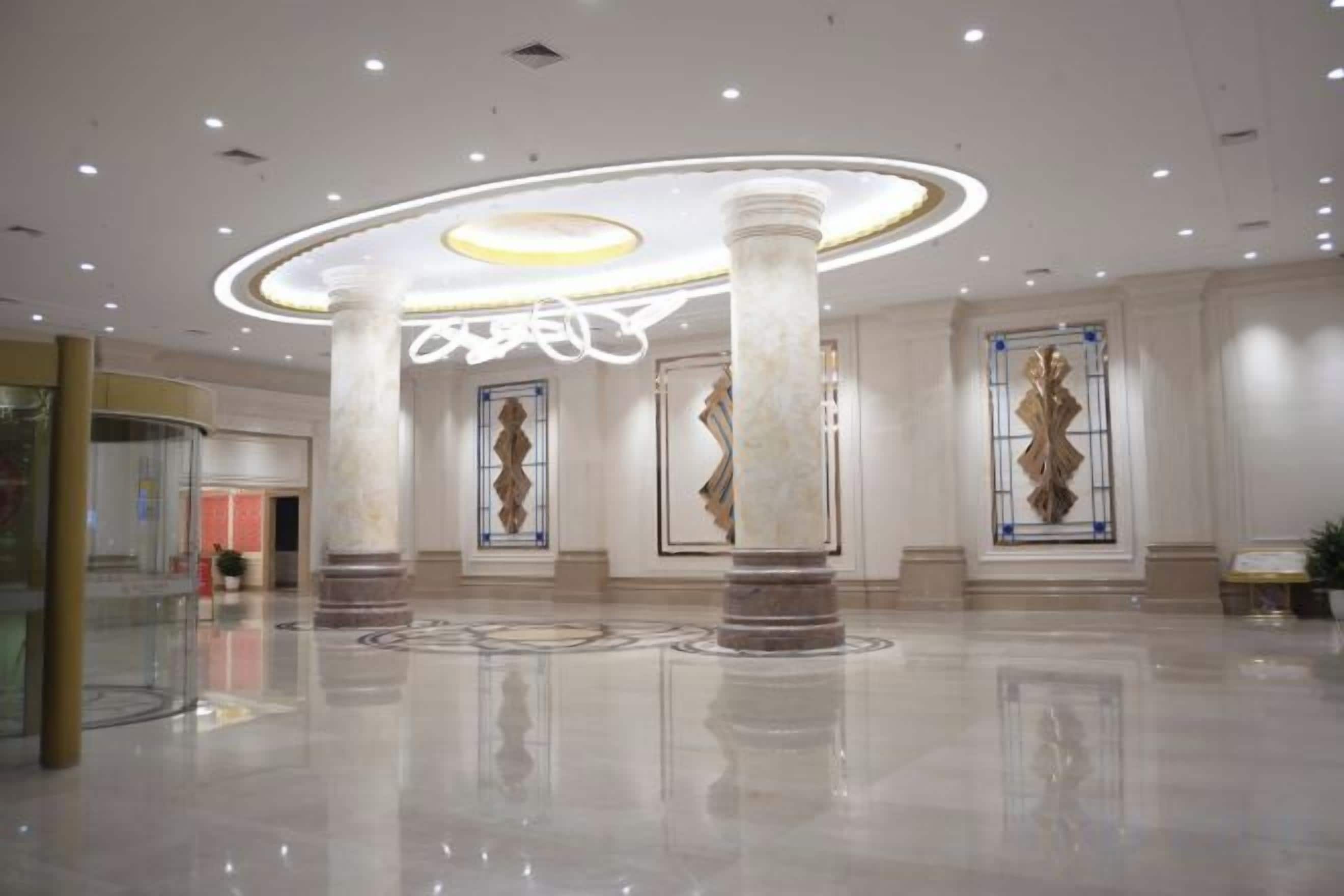A spacious lobby with high ceilings, large columns, and modern lighting fixtures.