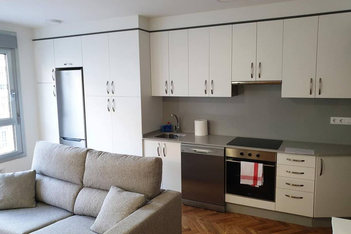 A modern kitchen with white cabinets, a built-in oven, and a dishwasher.