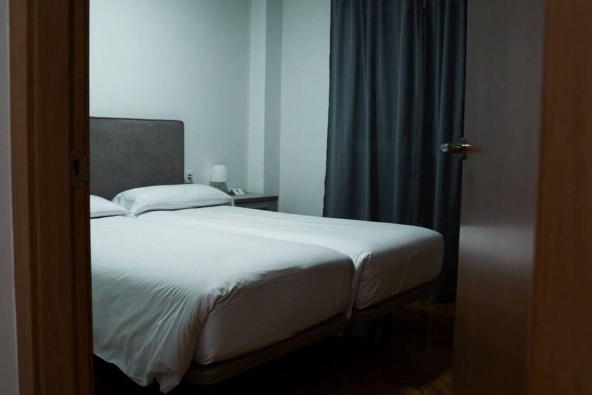 A bedroom with a bed, a nightstand, a lamp, and a door.