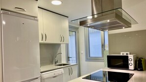 Une cuisine moderne avec des meubles blancs, une hotte en acier inoxydable, un four à micro-ondes encastré et un lave-vaisselle.