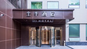Der Eingang eines Hotels mit einer Drehtür und einem Schild in einer Fremdsprache.