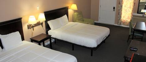 Una habitación de hotel con dos camas, un escritorio, una silla, una lámpara y una puerta.