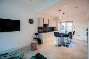A modern kitchen with white cabinets, a central island, and bar stools.
