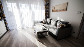 A modern living room with a sofa, coffee table, and a painting on the wall. - Apartamenty Bema od WroclawApartament-pl (Wroclaw)