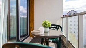 A balcony with a round table, a potted plant, and a white mug. - Apartamenty Bema od WroclawApartament-pl (Wroclaw)