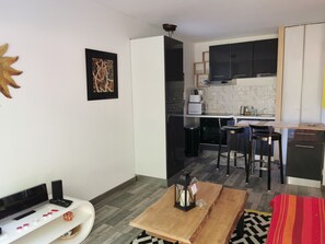 A modern kitchen with black cabinets, a white countertop, and a microwave. There is a wooden table with a lantern and a red and yellow striped blanket.