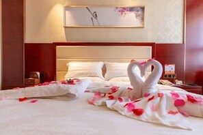 A hotel room with a bed, pillows, a nightstand, and a framed picture on the wall. - Jinyue International Hotel (Changtu)