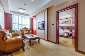 A hotel room with a sofa, armchair, TV, and a bed with a red headboard. - Jinyue International Hotel (Changtu)