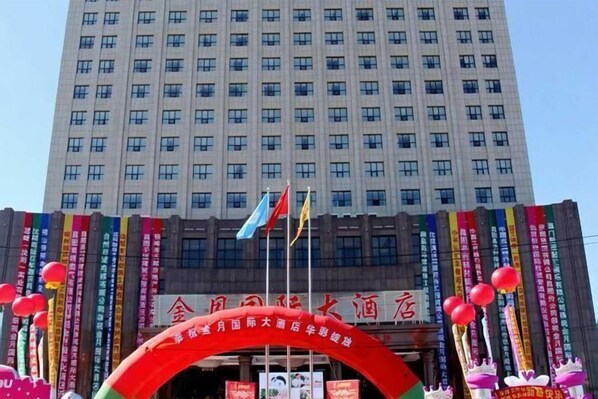 A hotel entrance with a red archway, flags, and banners. - Jinyue International Hotel (Changtu)