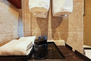 Un baño con toallero, cafetera y una bandeja negra.