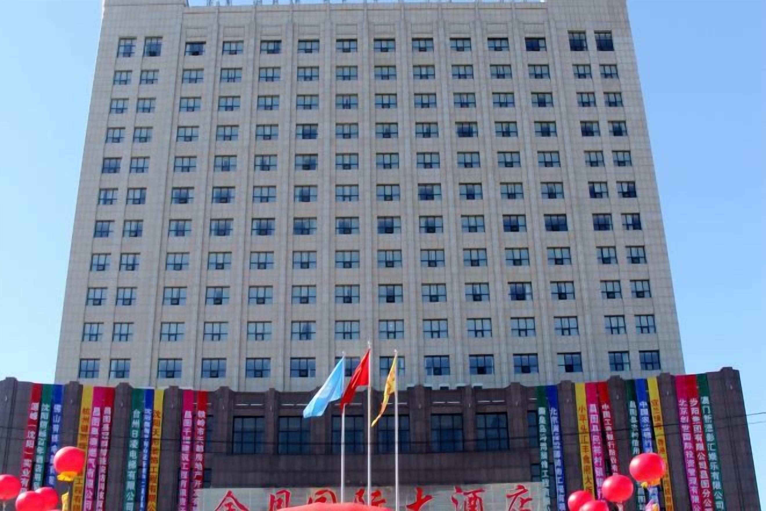 A tall building with multiple windows and flags.
