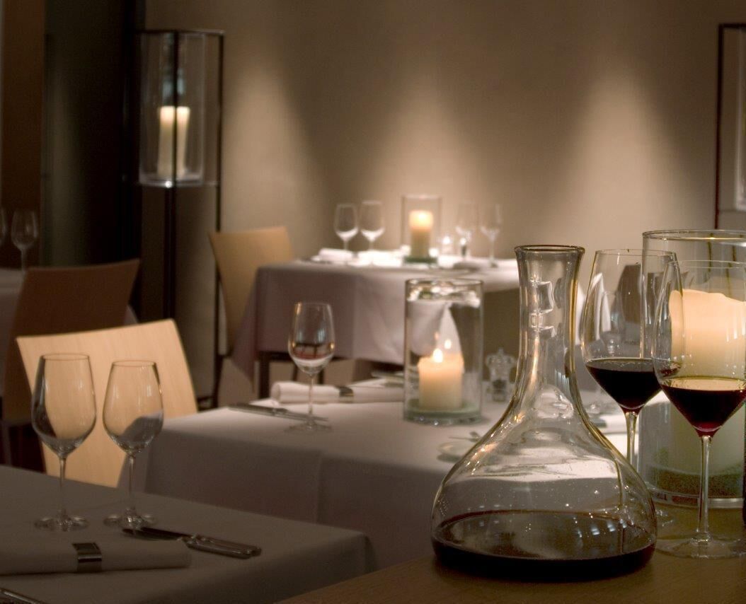 A dining table set with wine glasses, a decanter, and a candle, suggesting a romantic or intimate dining experience.