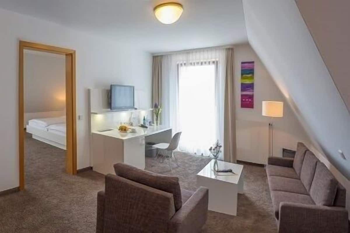 Een hotelkamer met een bed, een bureau met een computer, een televisie en een zithoek met stoelen en een bank.