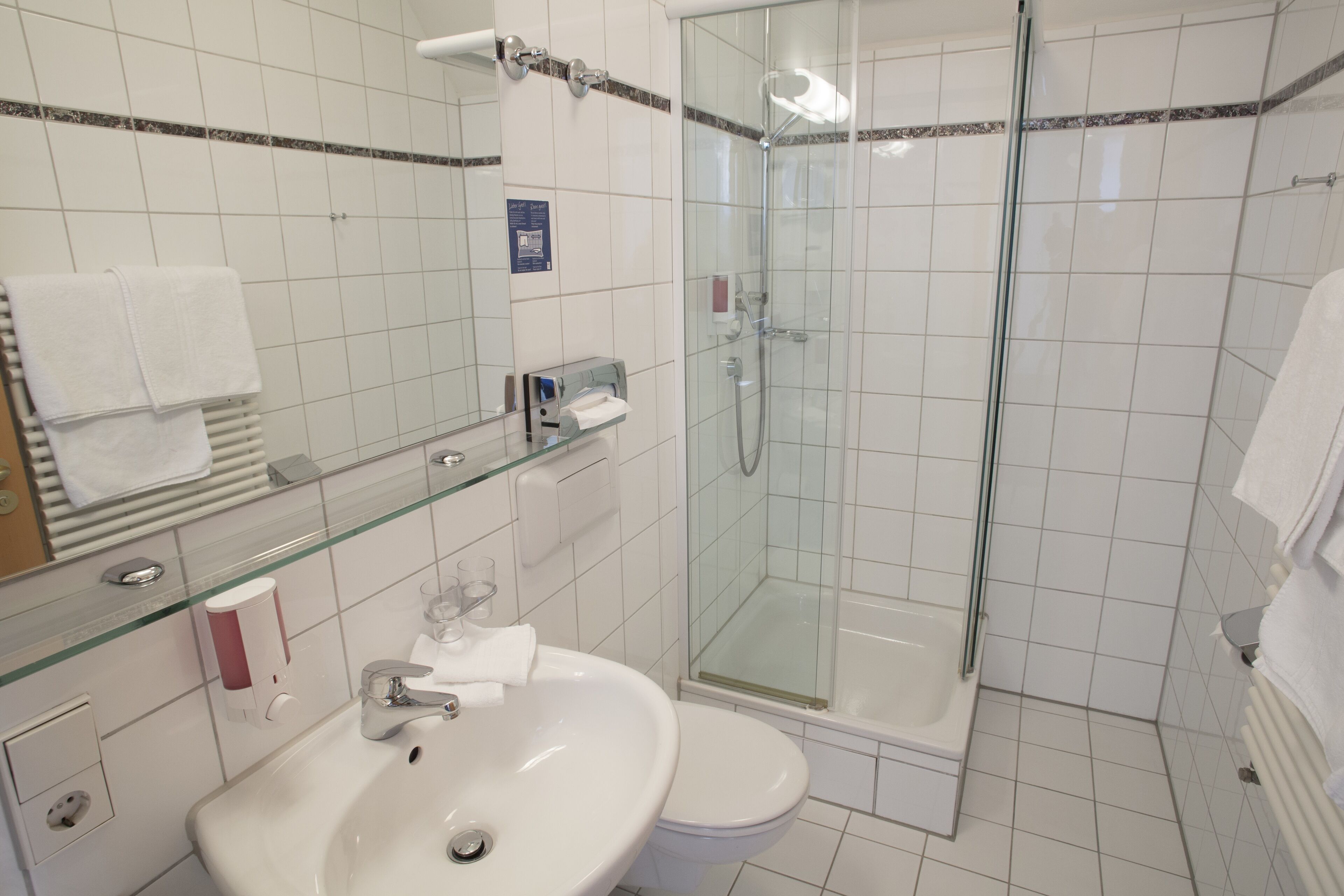 A modern bathroom with a glass-enclosed shower, a white sink, and a toilet.