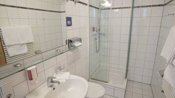A modern bathroom with a glass-enclosed shower, a white sink, and a toilet.