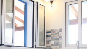 Eine moderne Küche mit weißen Schränken, einem Holztisch und einem Fenster mit Jalousien.