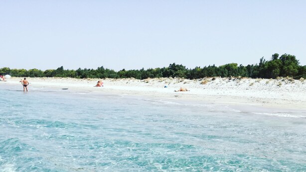 Una spiaggia con acque cristalline turchesi e una costa sabbiosa.
