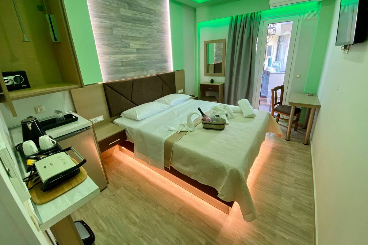 A hotel room with a bed, bedside table, and a desk with a coffee maker.