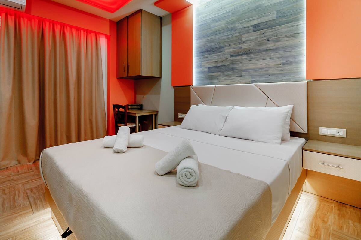 A neatly made bed with white linens and towels, a wooden headboard, and a bedside table with a drawer.