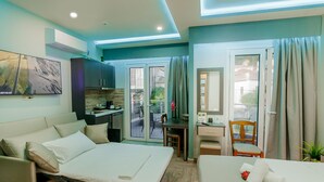 A modern hotel room with a bed, a desk, a sofa, and a balcony with a view. - Dim House (Parga)