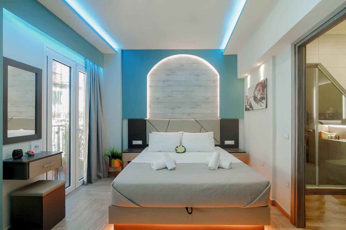 A modern bedroom with a large bed, bedside tables, a mirror, and a view of the outside.