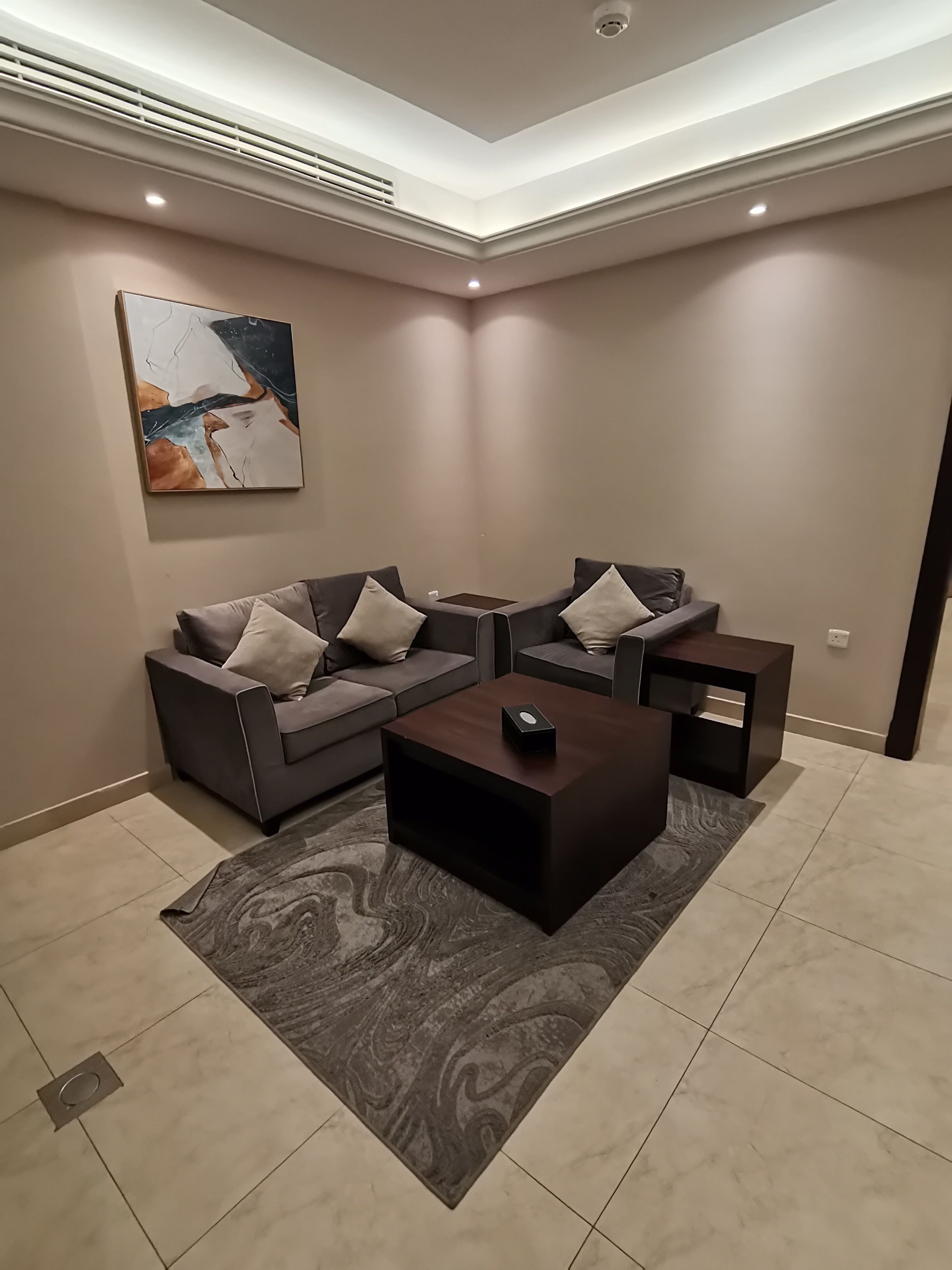 Un salon moderne avec un canapé d’angle, une table basse et un tapis.