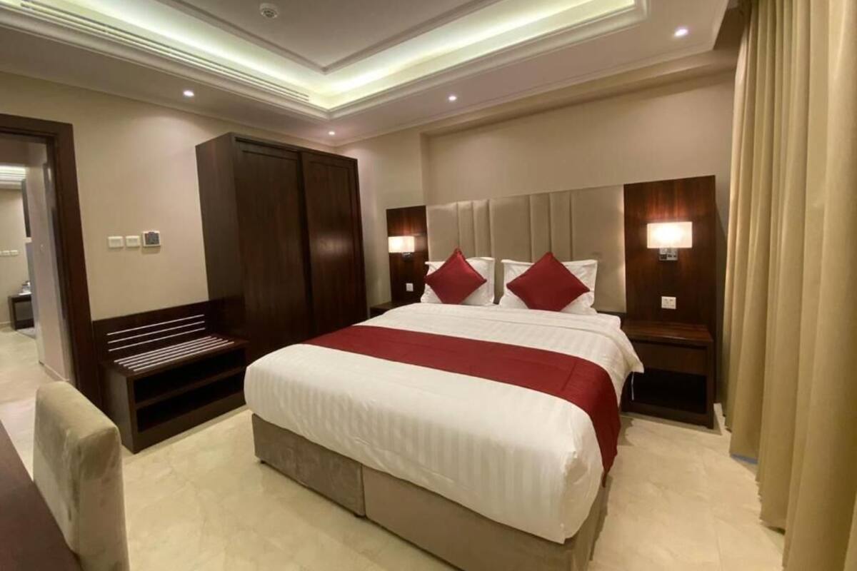 Una habitación de hotel con una cama grande, un armario, lámparas de noche e iluminación empotrada en el techo.