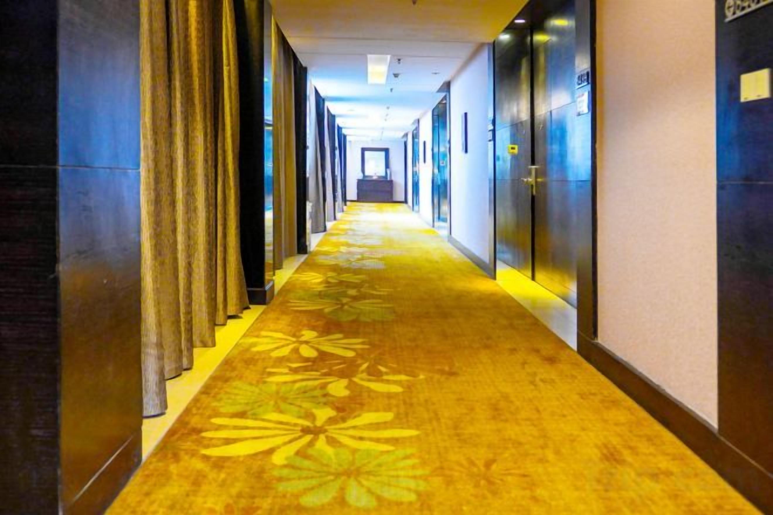 Ein Hotelgang mit Teppichboden, Türen auf beiden Seiten und einer Lichtquelle am Ende.