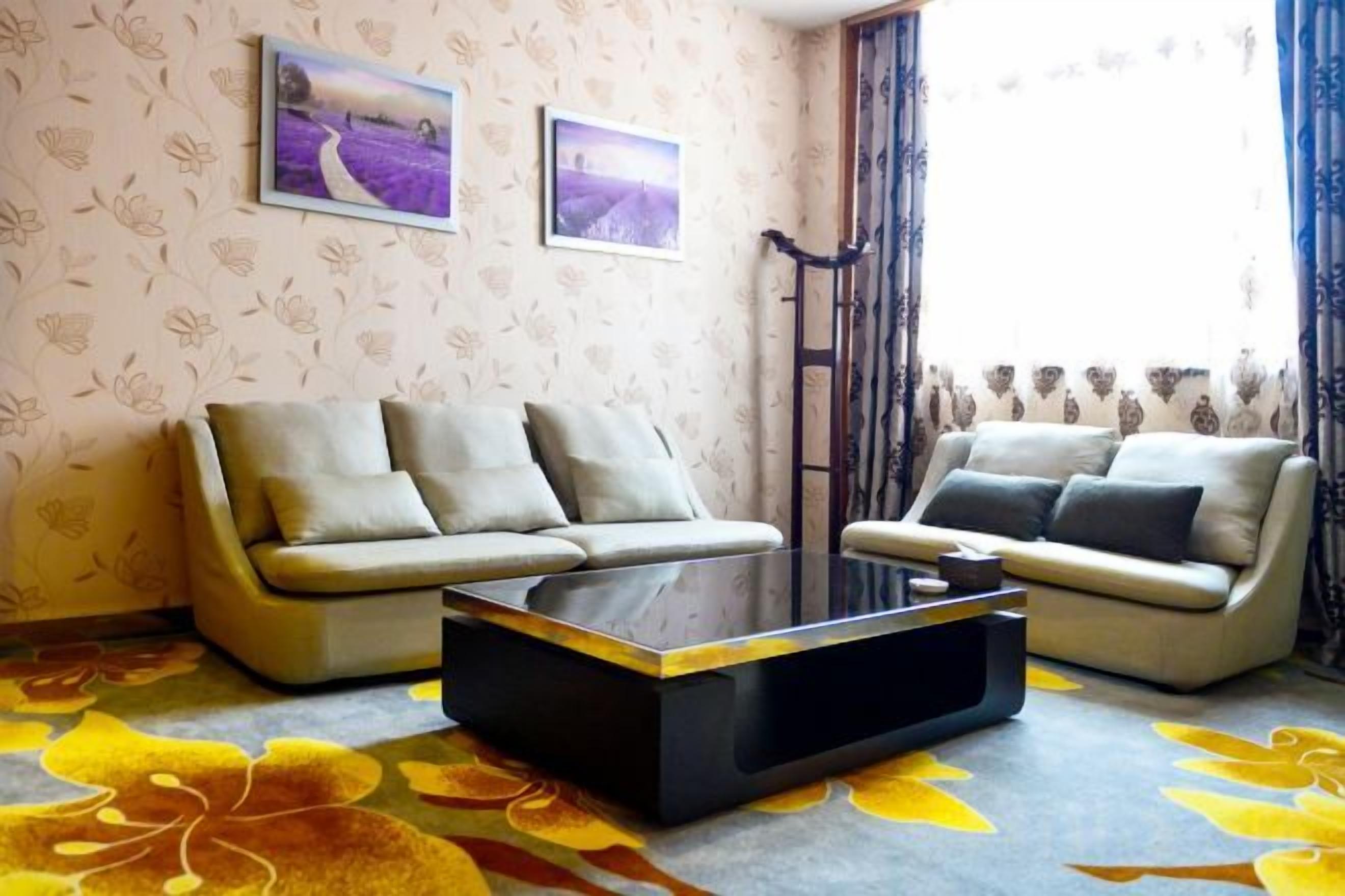 A living room with two sofas, a coffee table, and floral-patterned carpet.