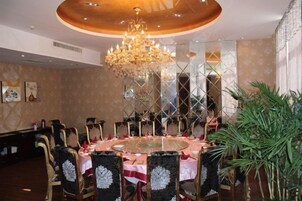 Un comedor con una mesa redonda, sillas y una araña.