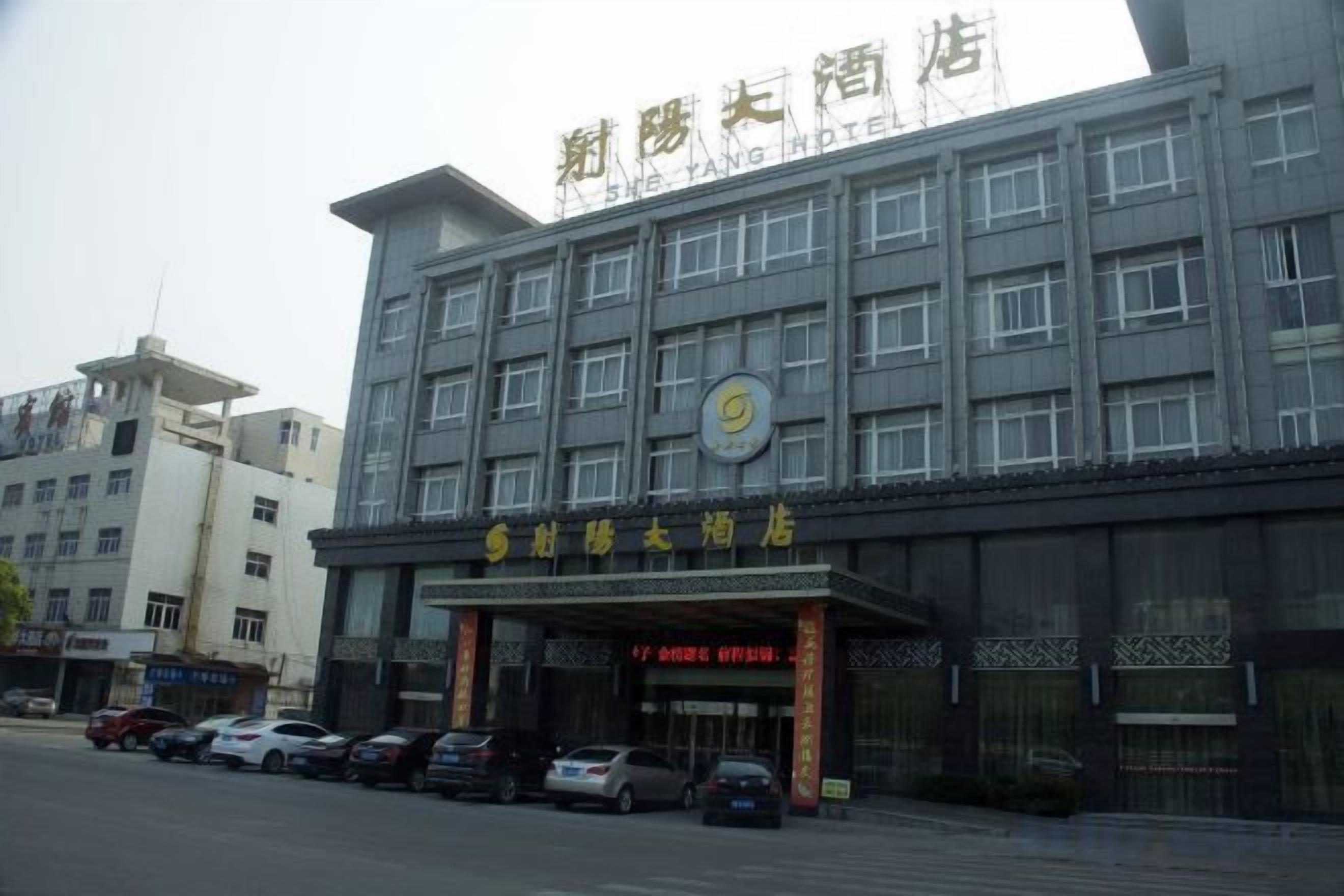 Un hotel con un cartello ben visibile, diversi piani e un parcheggio pieno di auto.