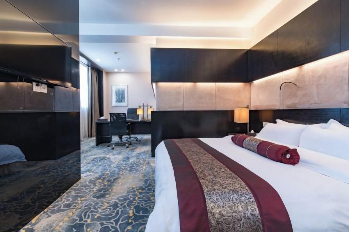 Ett hotellrum med en stor säng, ett skrivbord och en stol.