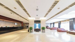 Un hall d’entrée spacieux avec un comptoir de réception, deux grandes colonnes et des espaces aménagés pour s’asseoir.