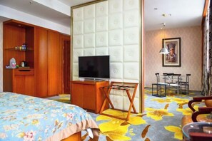 A hotel room with a bed, a TV, a wooden wardrobe, a small table, and a chair. - She Yang Hotel (Sheyang)