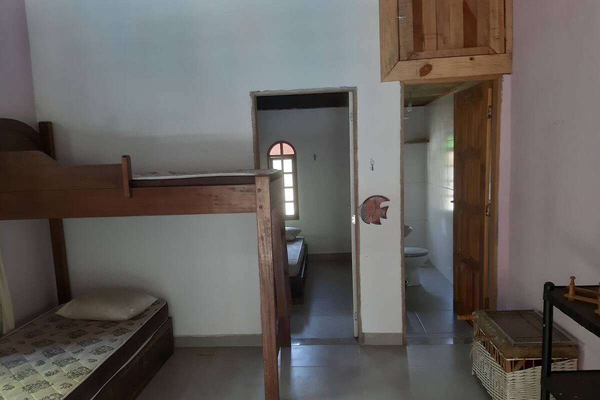 Une chambre avec un lit superposé, une armoire en bois, une petite table et un panier en osier.