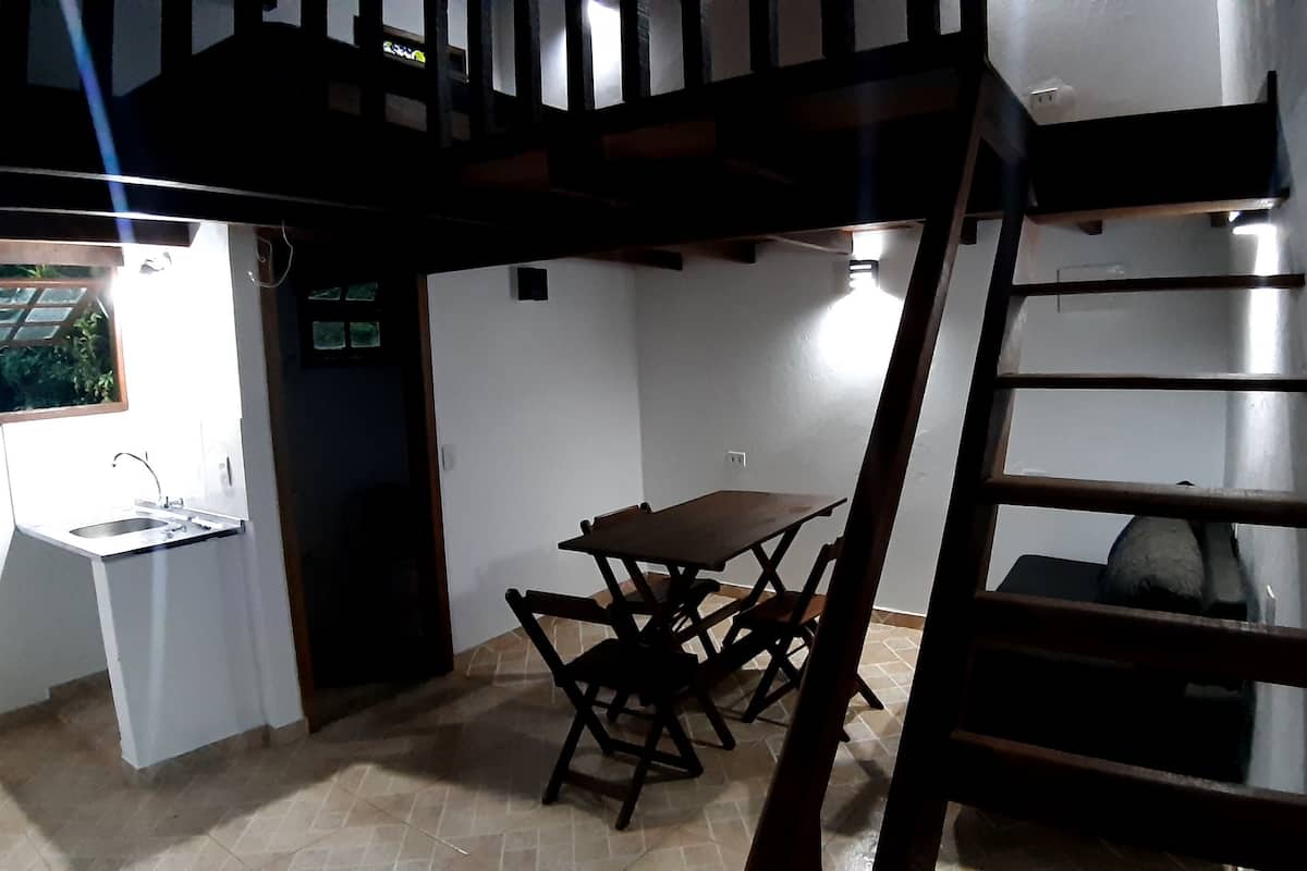Une cuisine compacte avec une table et des chaises, une petite fenêtre et une échelle en bois.