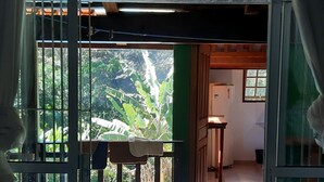 A room with a glass door leading to a pool area, a table, and a chair. - Chalé Vagalume em Boiçucanga (São Sebastião)