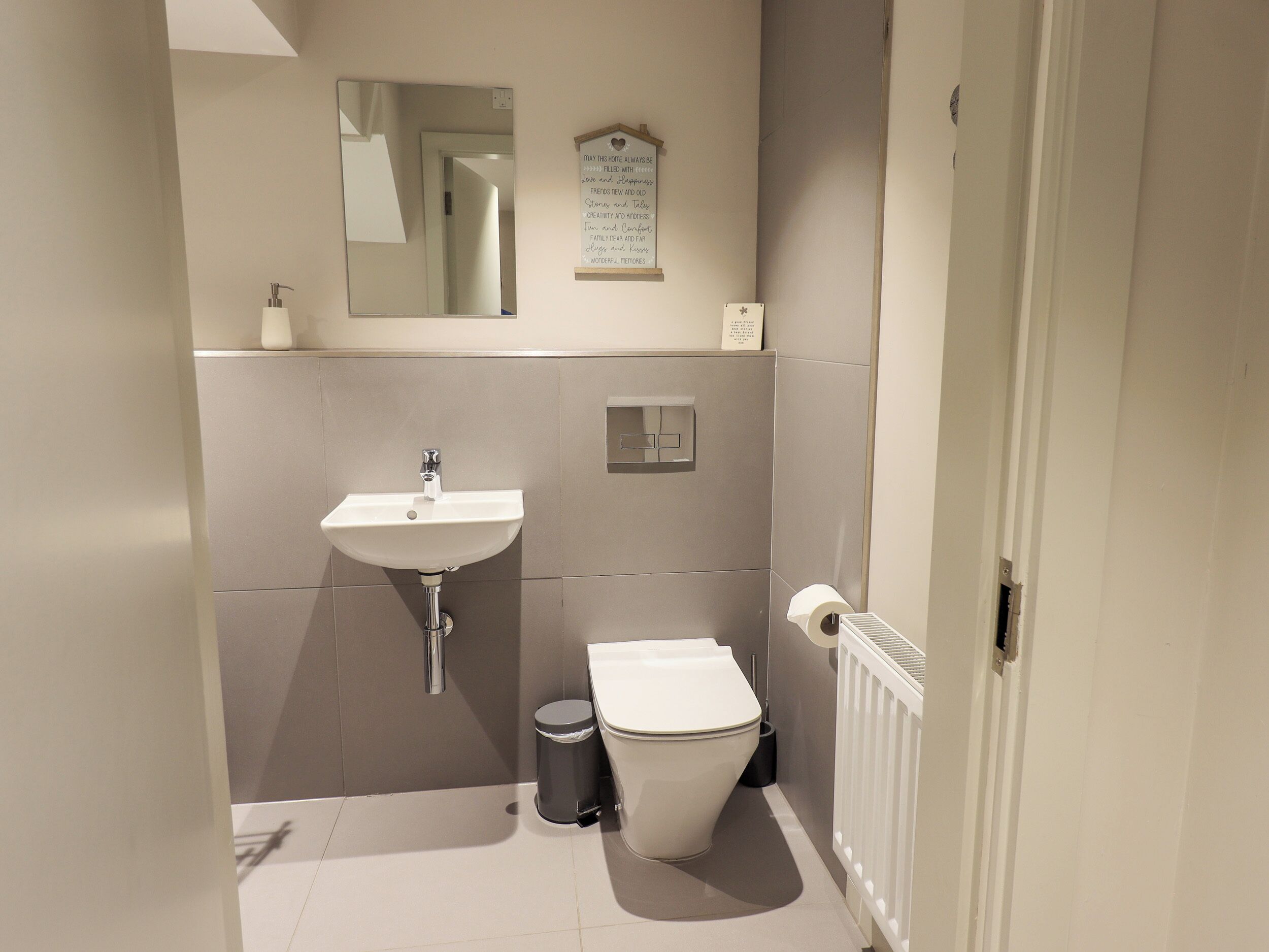 Ein kleines, modernes Badezimmer mit Waschbecken, Toilette und Mülleimer.