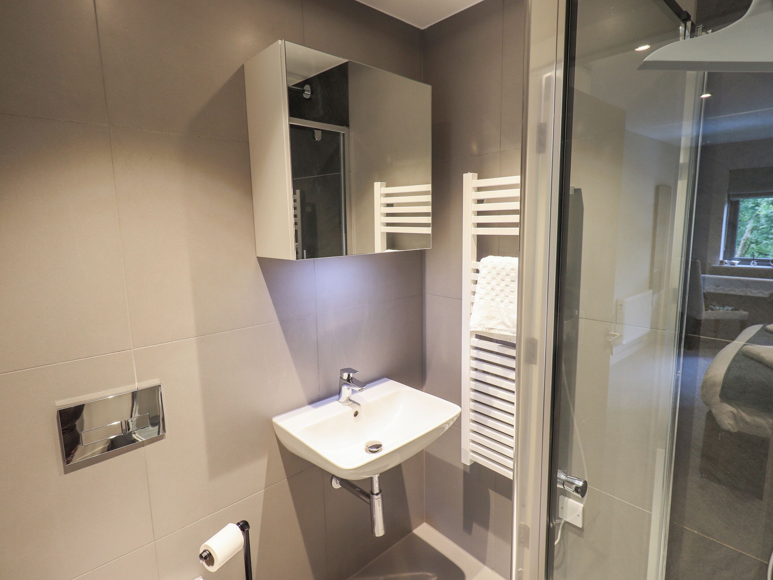Une salle de bain moderne avec une douche à parois de verre, un lavabo blanc et un porte-serviettes.