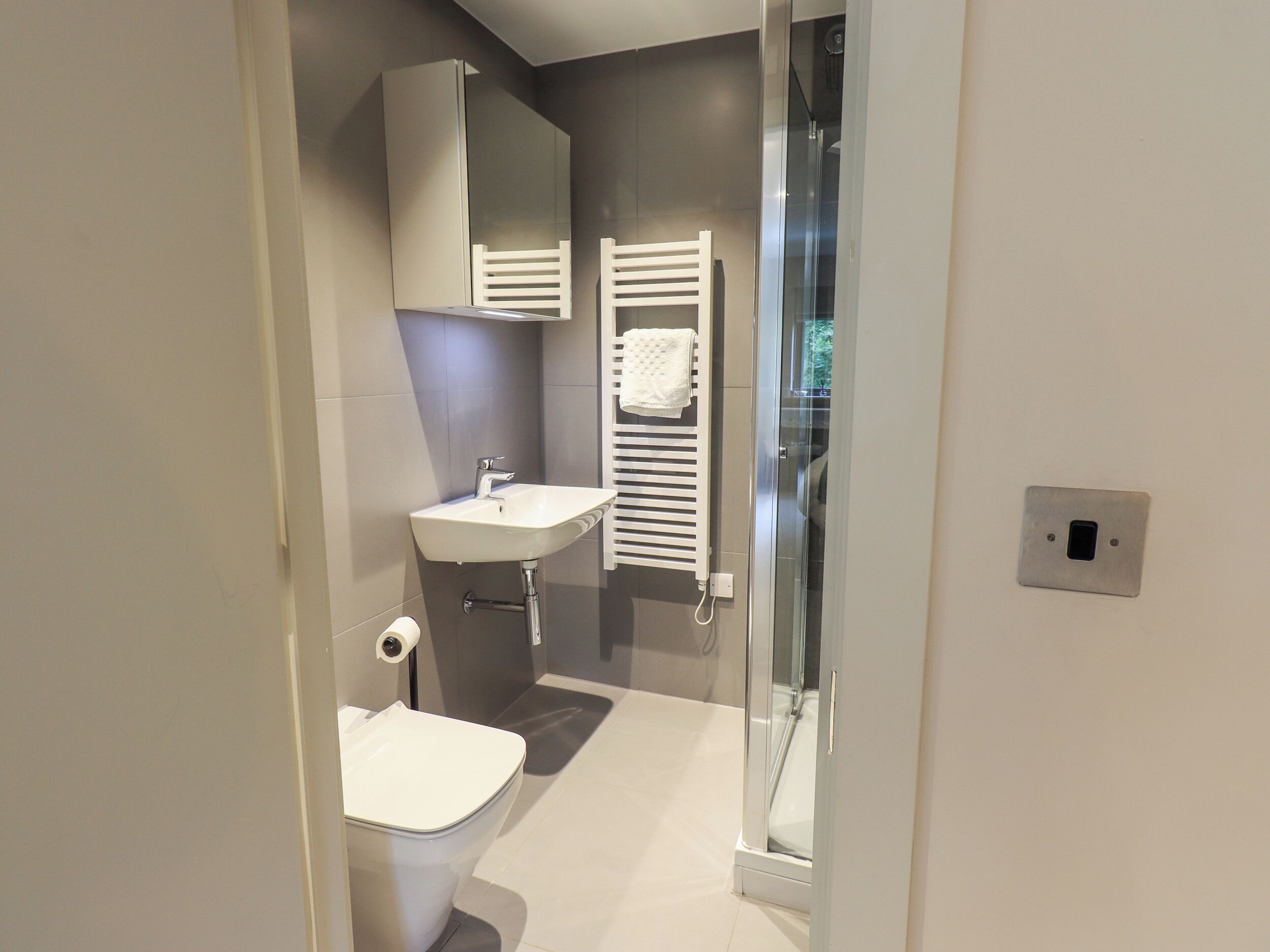Un baño moderno con inodoro, lavamanos y cabina de ducha de vidrio.