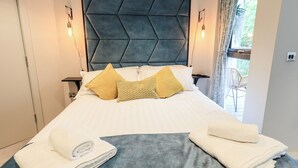 Una cama bien hecha con dos almohadas, un cabecero azul y dos lámparas de noche.