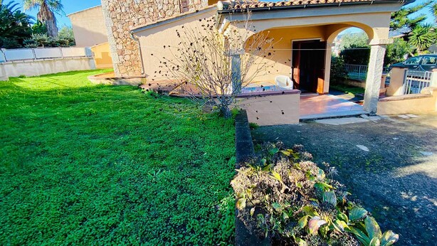 A two-story house with a stone facade, a tiled roof, and a well-maintained lawn. - Casa Vacanza Silvaredda (San Teodoro)