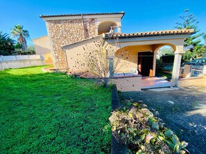Una casa de dos plantas con fachada de piedra, techo de tejas y un césped bien cuidado.